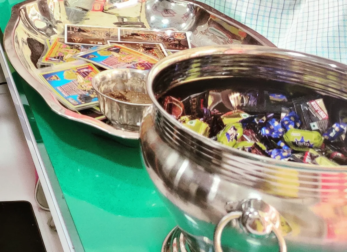 Brass and steel vessels and wrapped sweets set out on the shop counter